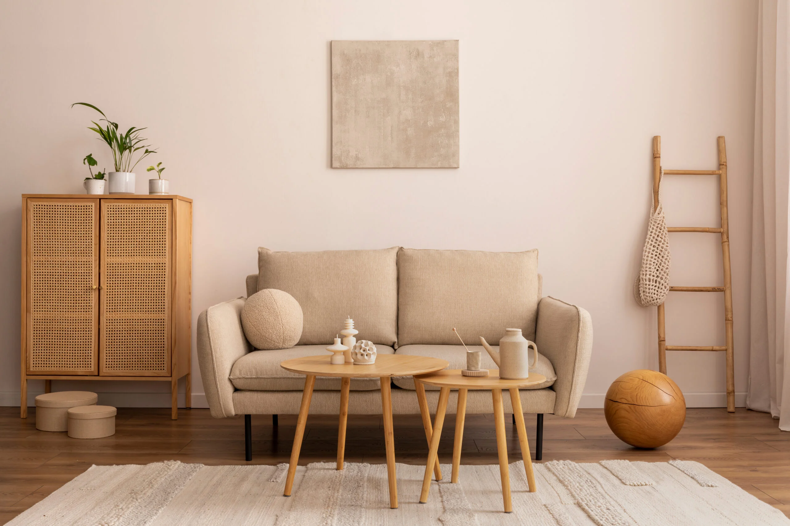 Interior design of cozy living room interior with mock up poster frame, beige sofa, round coffee table, vase with dried flowers, rug, rattan commode and personal accessories. Home decor. Template.